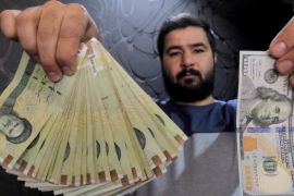 A money changer poses for the camera with a U.S hundred dollar bill (R) and the amount being given when converting it into Iranian rials (L), at a currency exchange shop in Tehran's business district, Iran, January 20, 2016. REUTERS/Raheb Homavandi/TIMA ATTENTION EDITORS - THIS IMAGE WAS PROVIDED BY A THIRD PARTY. FOR EDITORIAL USE ONLY.