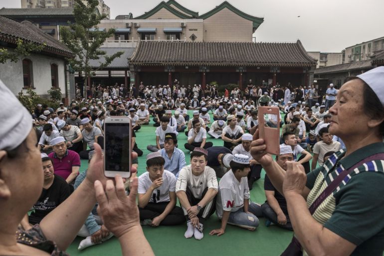 BEIJING, CHINA - JUNE 16: Chinese Hui Muslim men take photos as they wait on a carpet before Eid al-Fitr prayers marking the end of the holy fasting month of Ramadan at the historic Niujie Mosque on June 16, 2018 in Beijing, China. Islam in China dates back to the 10th century as the legacy of Arab traders who ventured from the Middle East along the ancient Silk Road. Of an estimated 23 million Muslims in China, roughly half are Hui, who are ethnically Chinese and speak