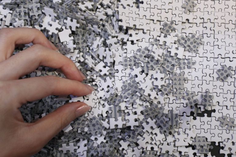 An employee of puzzle maker Beverly holds a piece of the company's white micro 1000 piece jigsaw puzzle at the International Toy Show in Tokyo June 14, 2012. The four-day event will open to public on Saturday, showcasing a total of about 35,000 products by 144 toy manufacturers. REUTERS/Yuriko Nakao (JAPAN - Tags: SOCIETY)