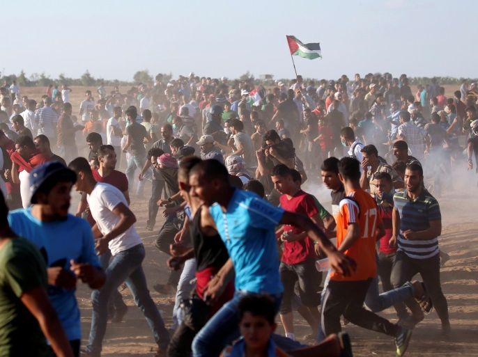 Palestinians run from Israeli fire and tear gas during a protest calling for lifting the Israeli blockade on Gaza and demanding the right to return to their homeland, at the Israel-Gaza border fence, in the southern Gaza Strip September 21, 2018. REUTERS/Ibraheem Abu Mustafa