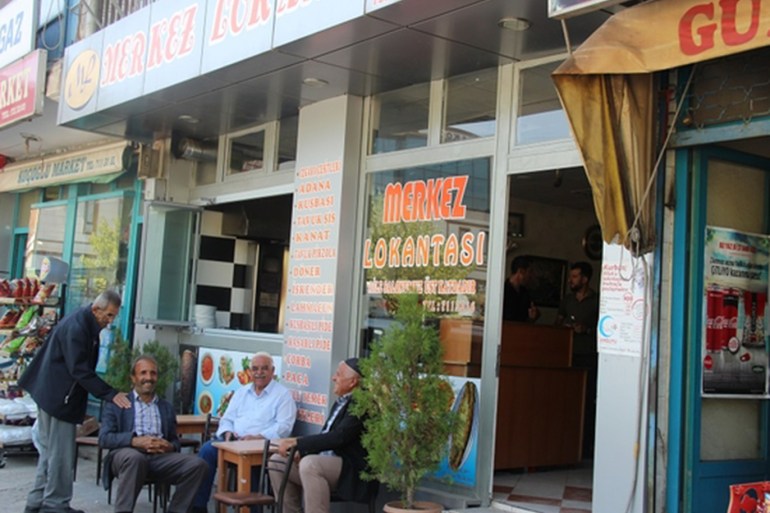 A group of locals of gathered for a tea in front of the Merkez restaurant in Karakoçan, Turkey (MEE/Zeyneb Varol)