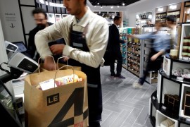 An employee prepares shopping bags inside a high-tech store named