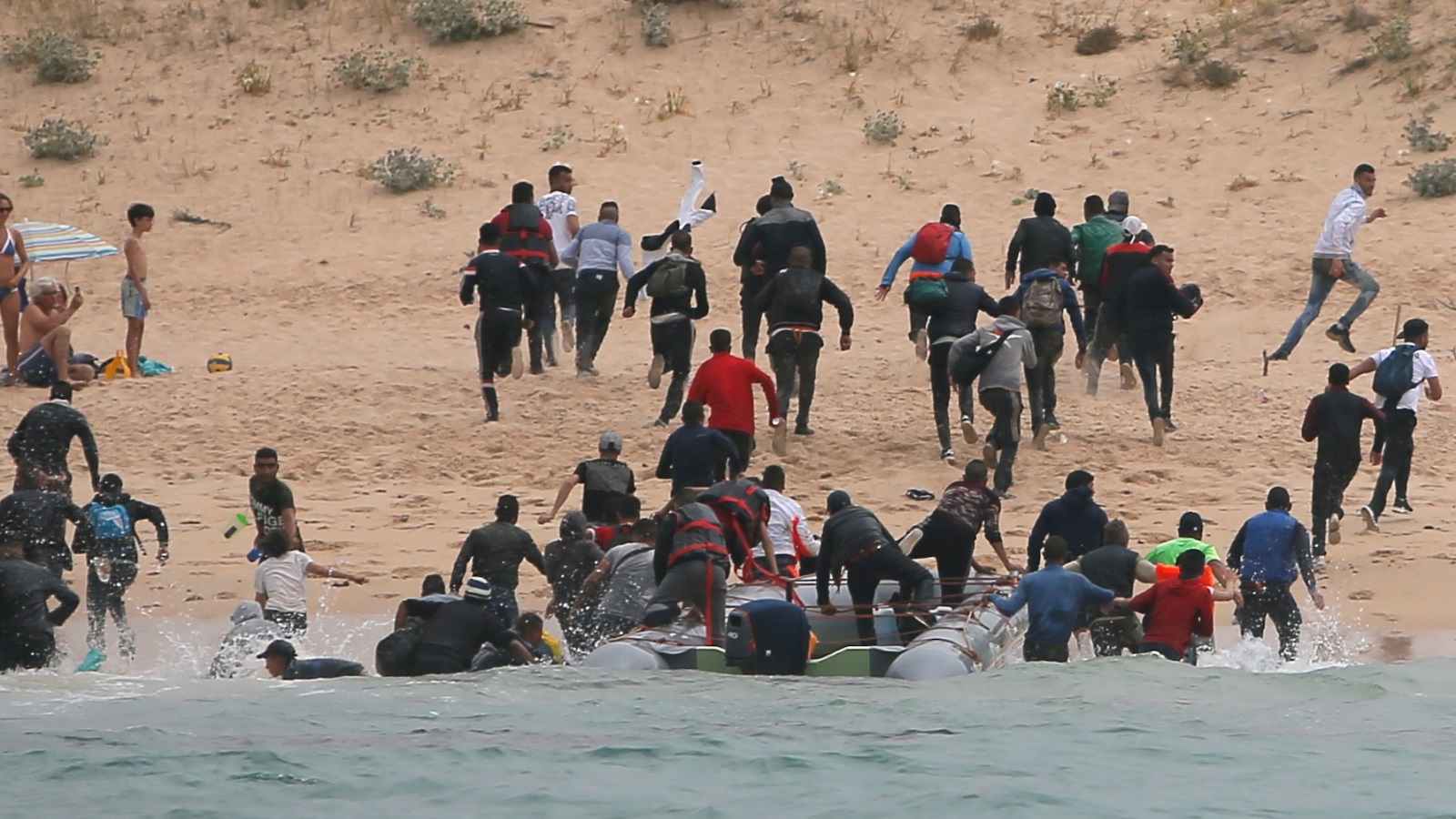 لحظة وصول مهاجرين غير نظاميين إلى سواحل إسبانيا على متن قارب مطاطي (رويترز)