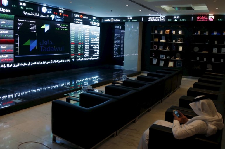 A trader uses his mobile as he monitors screens displaying stock information at the Saudi Stock Exchange (Tadawul) in Riyadh June 15, 2015. The chief executive of Saudi Arabia's stock exchange said on Monday he expected a flurry of licenses allowing the first foreign investors to buy shares there in coming weeks. To match Interview SAUDI-STOCKEXCHANGE/ REUTERS/Faisal Al Nasser