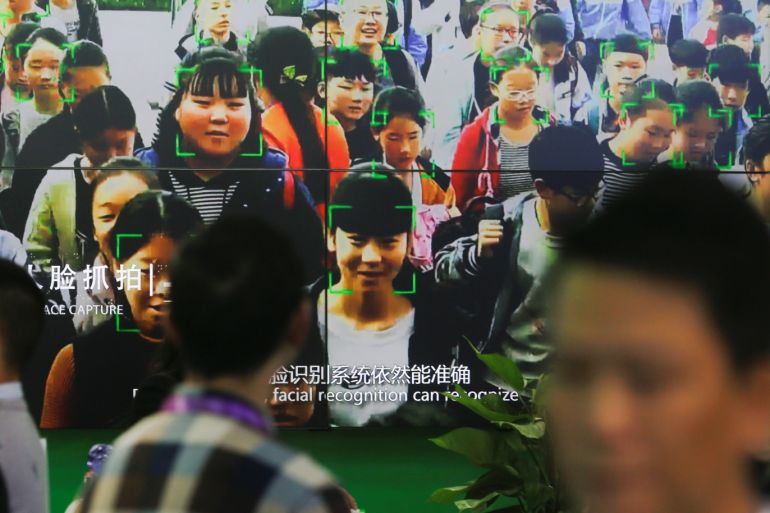 Visitors walk past a screen showing a demonstration of facial recognition software at the Security China 2018 exhibition on public safety and security in Beijing, China October 23, 2018. Picture taken October 23, 2018. REUTERS/Thomas Peter