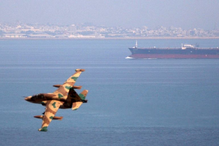 An Iranian military fighter plane flies past an oil tanker during naval manoeuvres in the Gulf and Sea of Oman April 5, 2006. REUTERS/Fars News/File Photo
