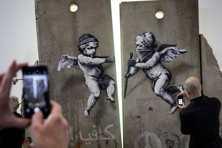Visitors take photographs of the 'replica separation barrier' created by British street artist Banksy as it stands on display at the Palestine tourist stand at the World Trade Fair at the Excel centre in London, Britain November 5, 2018. REUTERS/Simon Dawson TPX IMAGES OF THE DAY