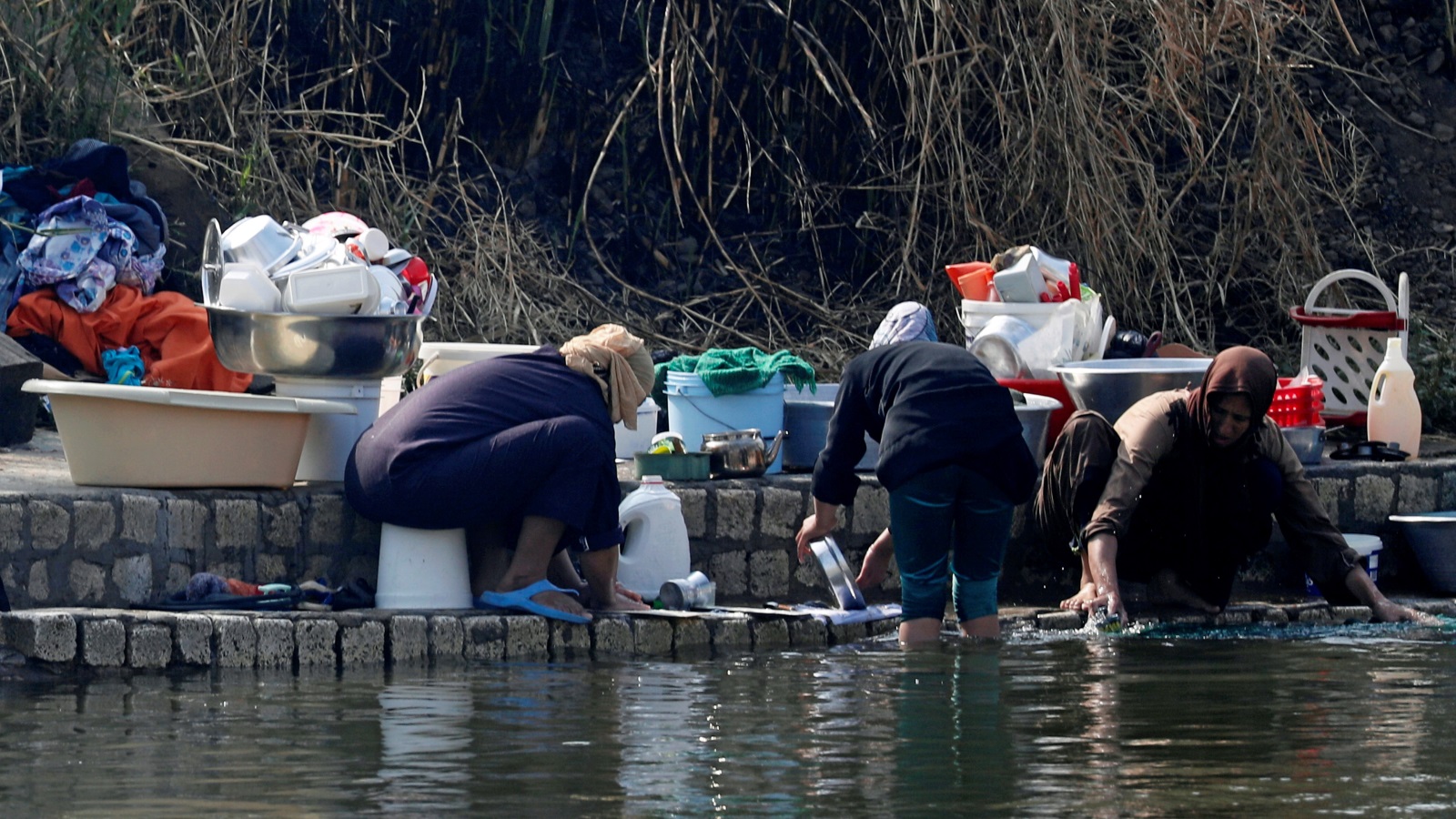‪نسوة يغسلن ملابس وأواني في نهر النيل بضواحي القاهرة‬ (رويترز)