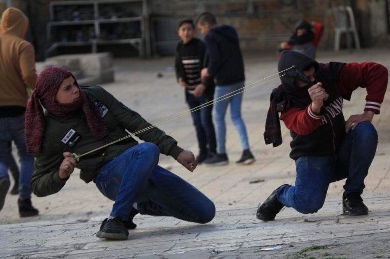 Israeli forces intervene in a protest in Hebron- - HEBRON, WEST BANK - DECEMBER 14: Palestinians throw rock in response to Israeli intervention to a protest against the Israeli raids to Palestinians' homes in Hebron, West Bank on December 14, 2018.