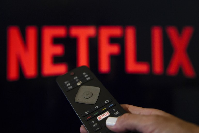 Digital Applications- - ANKARA, TURKEY - JULY 18 : A person holds a Netflix remote control in front of the logo of Netflix application in Ankara, Turkey on July 18, 2018.