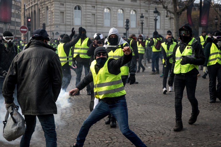 PARIS, FRANCE - DECEMBER 08: A protester throws a tear gas canister back at the police during the 'yellow vests' demonstration near the Arc de Triomphe on December 8, 2018 in Paris France. ''Yellow Vests' ('Gilet Jaunes' or 'Vestes Jaunes') is a protest movement without political affiliation which was inspired by opposition to a new fuel tax. After a month of protests, which have wrecked parts of Paris and other French cities, there are fears the movement has b