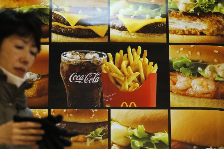 A woman walks past an advertisement showing McDonald's burgers, fries and a drink, outside a McDonald's store in Tokyo December 16, 2014. McDonald's Holdings Co (Japan) Ltd has embarked on the emergency measure of only offering small-sized french fries to customers as a protracted labour dispute at U.S. West Coast ports has contributed to long delays in imports. REUTERS/Issei Kato (JAPAN - Tags: BUSINESS EMPLOYMENT)