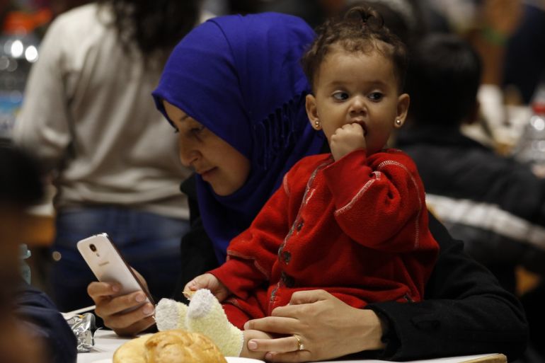 A migrant woman from Syria checks her mobile device as she eats with her daughter at a recetion centre after their arrival at the main railway station in Dortmund, Germany September 13, 2015. Germany re-imposed border controls on Sunday after Europe's most powerful nation acknowledged it could scarcely cope with thousands of asylum seekers arriving every day. REUTERS/Ina Fassbender
