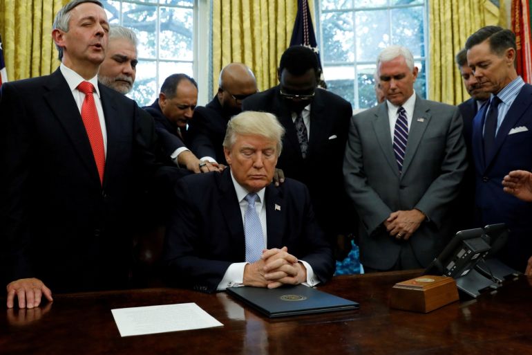 Faith leaders place their hands on the shoulders of U.S. President Donald Trump as he takes part in a prayer for those affected by Hurricane Harvey in the Oval Office of the White House in Washington, U.S., September 1, 2017. REUTERS/Kevin Lamarque TPX IMAGES OF THE DAY