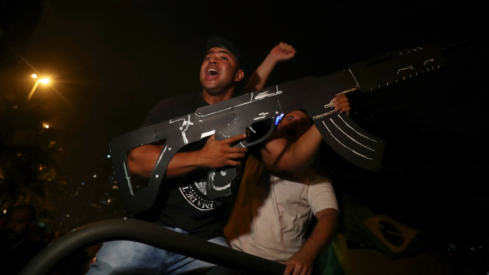 ‪(رويترز)‬ مؤيد للرئيس البرازيلي الجديد يحمل سلاحا كرتونيا