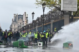 Yellow vest protest against rising fuel taxes in Paris- - PARIS, FRANCE - DECEMBER 01: Yellow vests (gilets jaunes) protesters protect themselves against fire tear gas and water cannon during clash with riot police on Rue de Rivoli, as part of demonstration against rising fuel taxes in Paris, France on December 01, 2018.