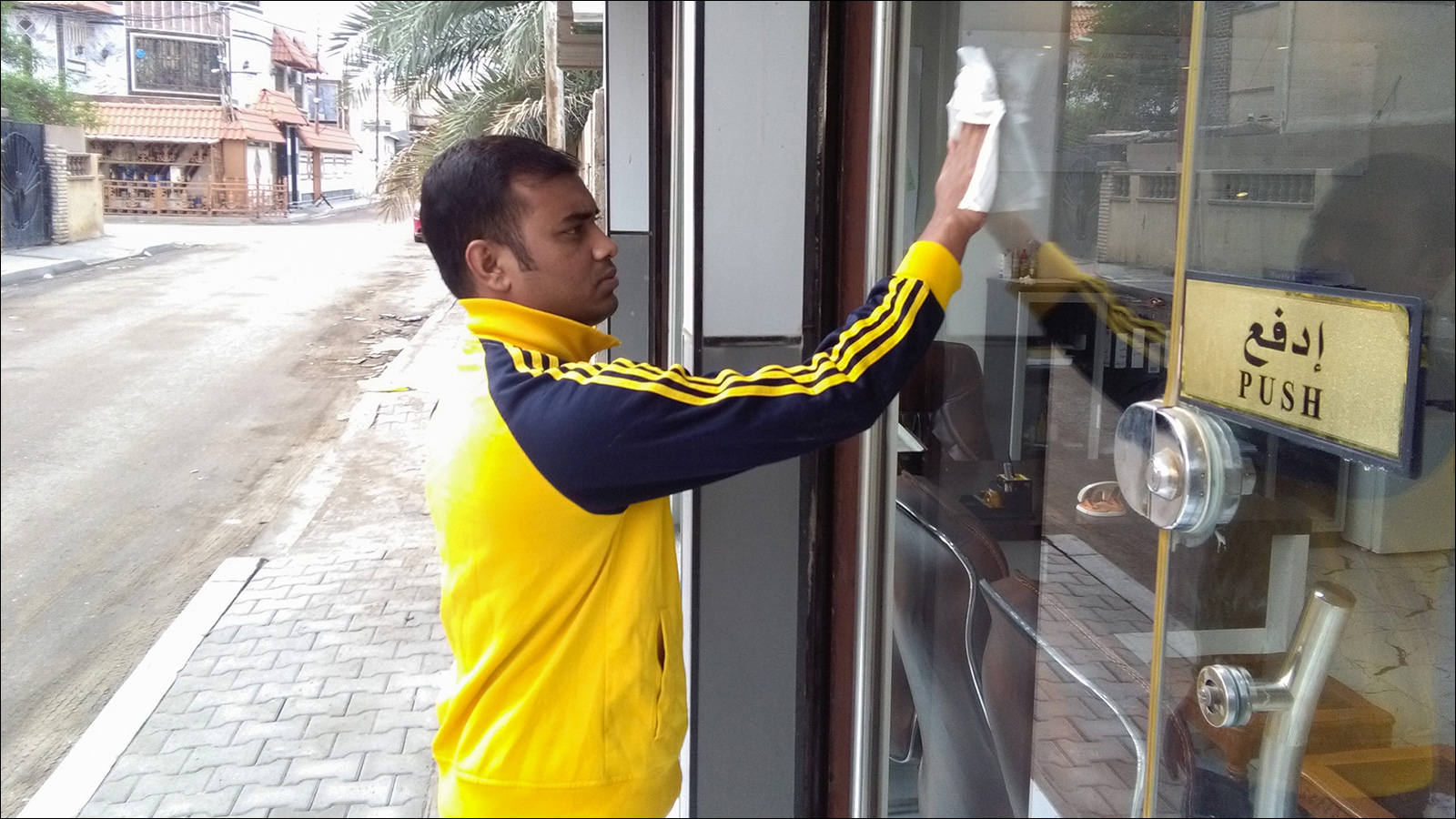 ضياء الدين ينظف زجاج أحد المحلات في البصرة (الجزيرة نت)