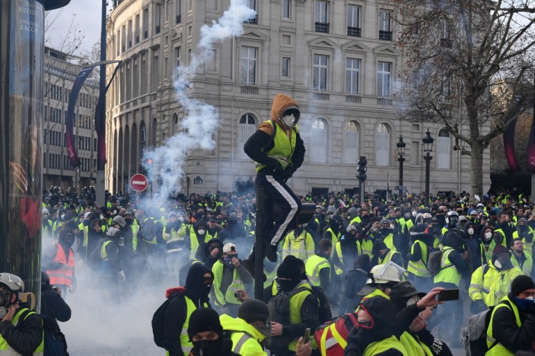 PARIS, FRANCE - DECEMBER 08: Tear gas is thrown as demonstrators take part in the demonstration of the yellow vests near the Arc de Triomphe on December 08, 2018 in Paris France. ''Yellow Vests' ('Gilet Jaunes' or 'Vestes Jaunes') is a protest movement without political affiliation which was inspired by opposition to a new fuel tax. After a month of protests, which have wrecked parts of Paris and other French cities, there are fears the movement has been infiltra