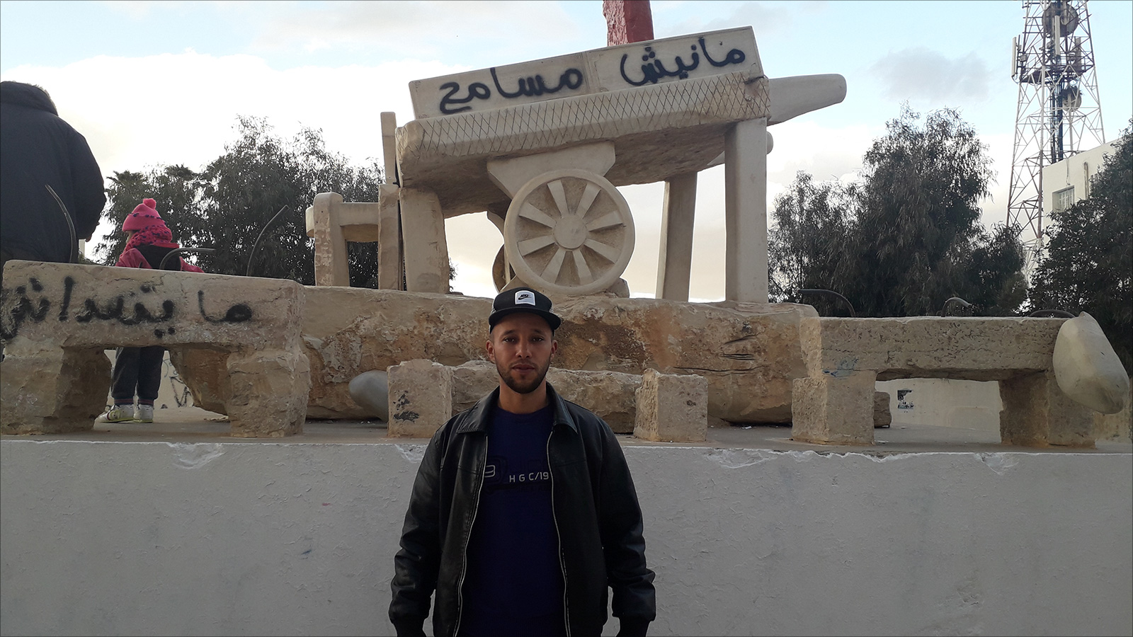 ‪بلال الغربي من شباب الثورة أمام مجسم لعربة البوعزيزي‬ (الجزيرة نت)