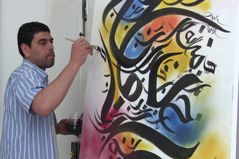 صفوان ميلاد يضع اخر اللمسات على لوحة للخط العربي ويضفي عليها الوانا حية (الجزيرة نت)