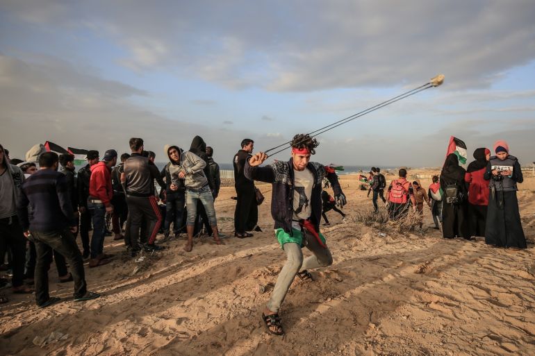“Maritime protest” in Gaza- - GAZA CITY, GAZA - DECEMBER 17: Palestinians throw stones with slingshots in response to Israeli forces' intervention with gas bombs during “maritime protest” against Israel’s ongoing blockade of Gaza on the strip’s northern coast, in Gaza on December 17, 2018. They demand an end to Israel’s 12-year blockade of the strip, which has gutted Gaza’s economy and deprived its roughly 2 million inhabitants of many basic commodities.