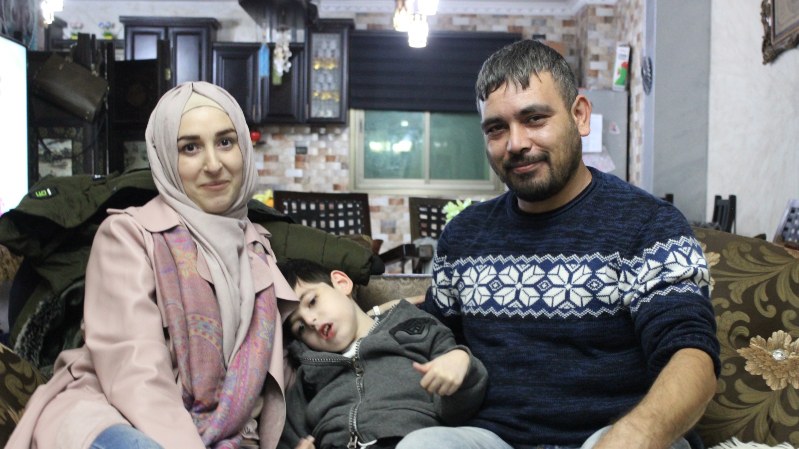 رامي جابر وزوجته سلمى مع طفلهما المصاب بالتوحد فريد (الجزيرة)
