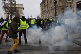 PARIS, FRANCE - DECEMBER 08: People are surrounded by tear gas during the demonstration of the yellow vests near the Champs-Elysees avenue on December 08, 2018 in Paris France. 'Yellow Vests' ('Gilet Jaunes' or 'Vestes Jaunes') is a protest movement without political affiliation that protests against taxes and rising fuel prices. The 'Yellow Vest' protests have wrecked parts of Paris and other French cities for nearly a month, as the movement - inspired by oppos