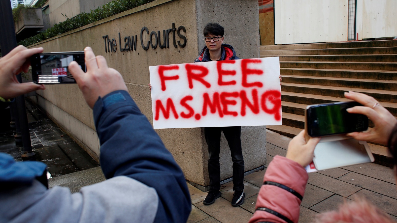 متظاهر أمام المحكمة يطالب بإطلاق سراح منغ وان تشو(رويترز)