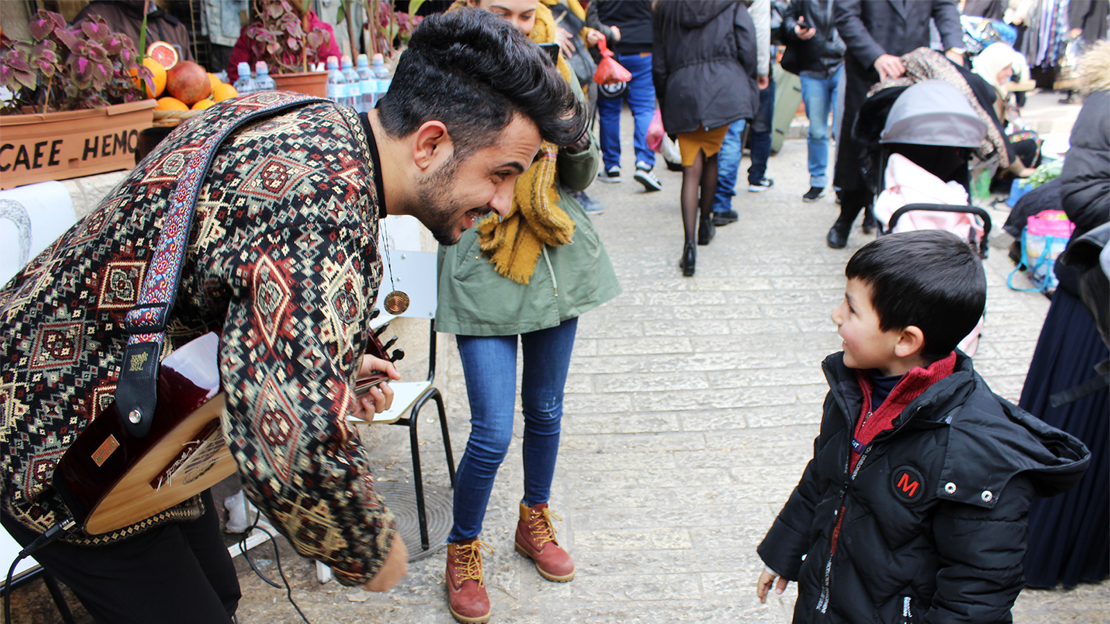 كنعان الغول أثناء تفاعله مع أحد الأطفال في العرض الموسيقي داخل أسوار القدس (الجزيرة)