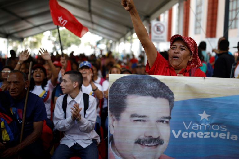 A supporter of Venezuela's President Nicolas Maduro holds a banner depicting him as he takes part in a gathering outside the Miraflores Palace in Caracas, Venezuela January 26, 2019. REUTERS/Carlos Garcia Rawlins