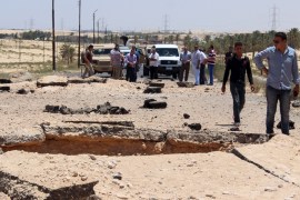 Egyptian security officials inspect the site of a bomb blast targeted at soldiers, on the highway between Al-Arish and the border town of Rafah, in the troubled northern part of the Sinai peninsula, July 9, 2015. Giant posters of Egyptian President Abdel Fattah al-Sisi in military uniform hang at security checkpoints leading to the Sinai, but the crash of a Russian airliner in the peninsula has shattered the image of control they seek to project. Picture taken July 9, 2
