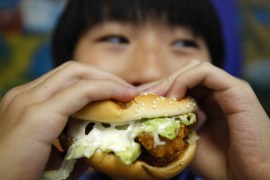 A boy poses with a chicken burger at a fast food outlet in Taipei January 29, 2010. The Taiwan Department of Health on Thursday proposed a ban on junk food advertisements aired around children's television programmes, to tackle the growing child obesity rate, said officials. REUTERS/Nicky Loh (TAIWAN - Tags: SOCIETY FOOD HEALTH MEDIA)