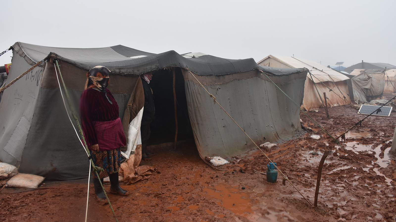 نازحة سورية أمام خيمتها التي غمرتها المياه (الجزيرة نت)