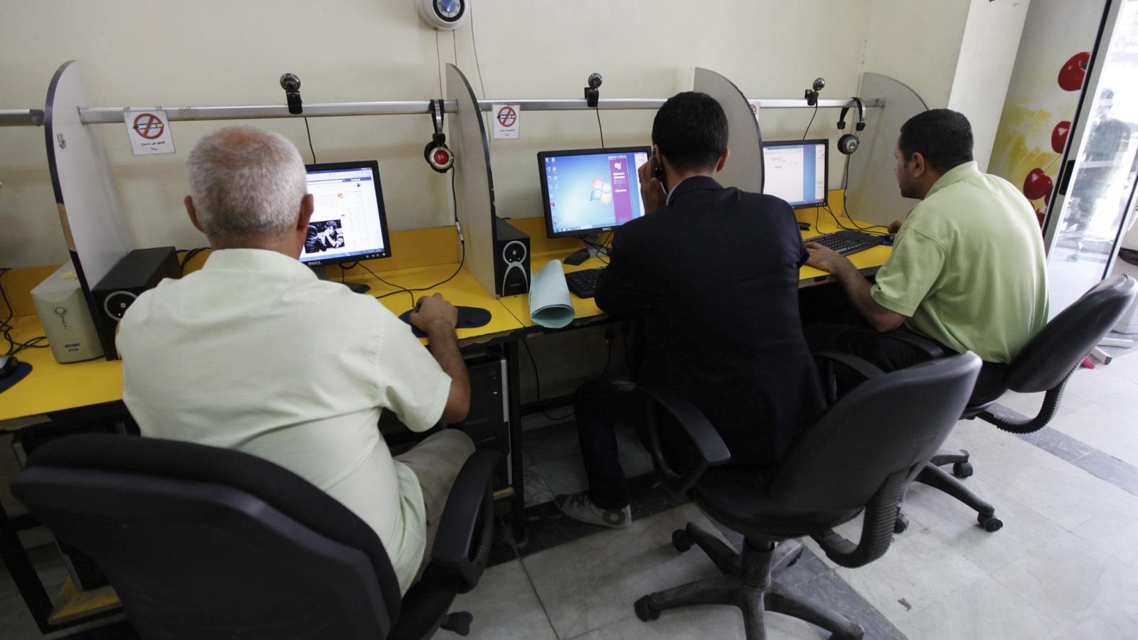 ‪عراقيون يبحرون في عالم الإنترنت داخل أحد المقاهي في بغداد‬ (رويترز)