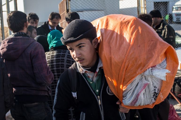 A young man stands with supplies as he waits for transport to take him back to Syria as a small number of Syrian refugees were allowed to return to Syria at the closed Turkish border gate on February 9, 2016 in Kilis, Turkey.