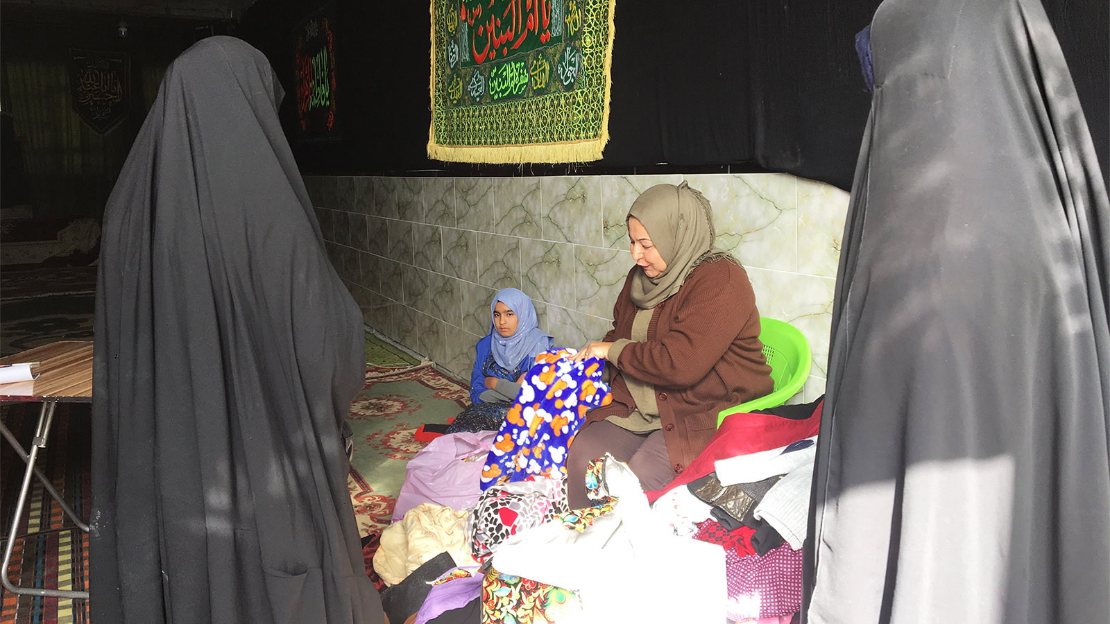 فاطمة الموسوي أثناء توزيعها المساعدات على الأيتام والفقراء (الجزيرة نت)