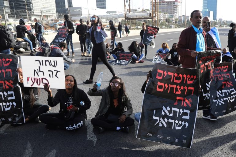 Israelis protesters, some of Ethiopian decent, hold placards as they block a highway during a demonstration against police brutality, following the death of an Israeli Ethiopian community member, Yehuda Biadga, in Tel Aviv, Israel January 30, 2019. The placard with Hebrew writing reads: