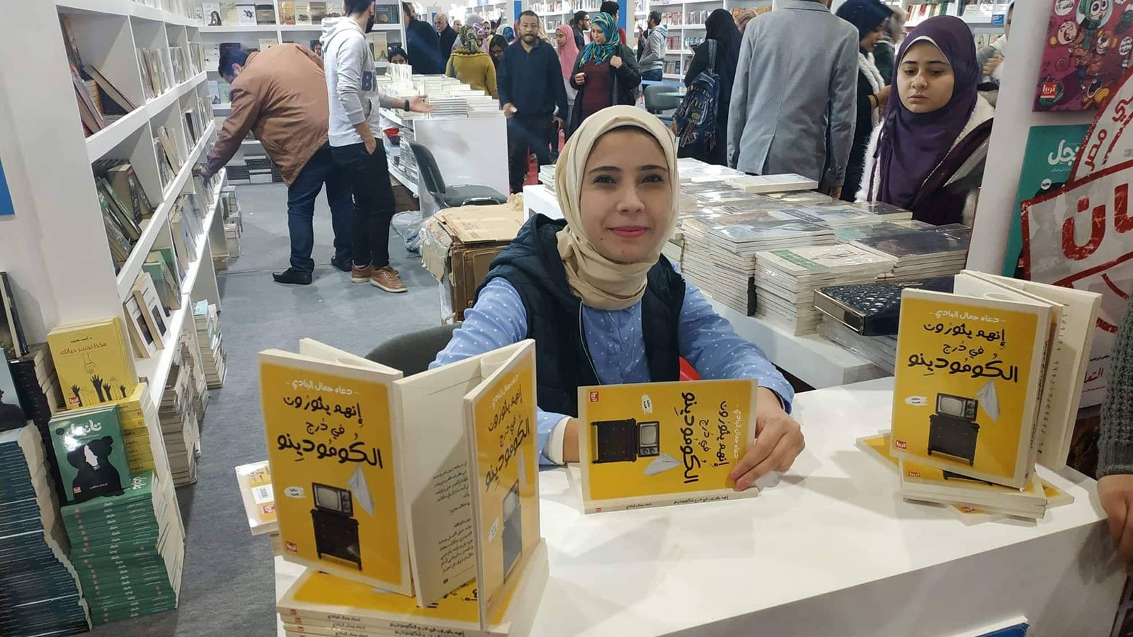 ‪الكاتبة دعاء البادي مع روايتها الأخيرة بمعرض‬ (الجزيرة)