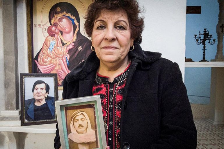 Salwa Salem Copty holds photos of her father and mother in the church in Ma'alul village (Mati Milstein)