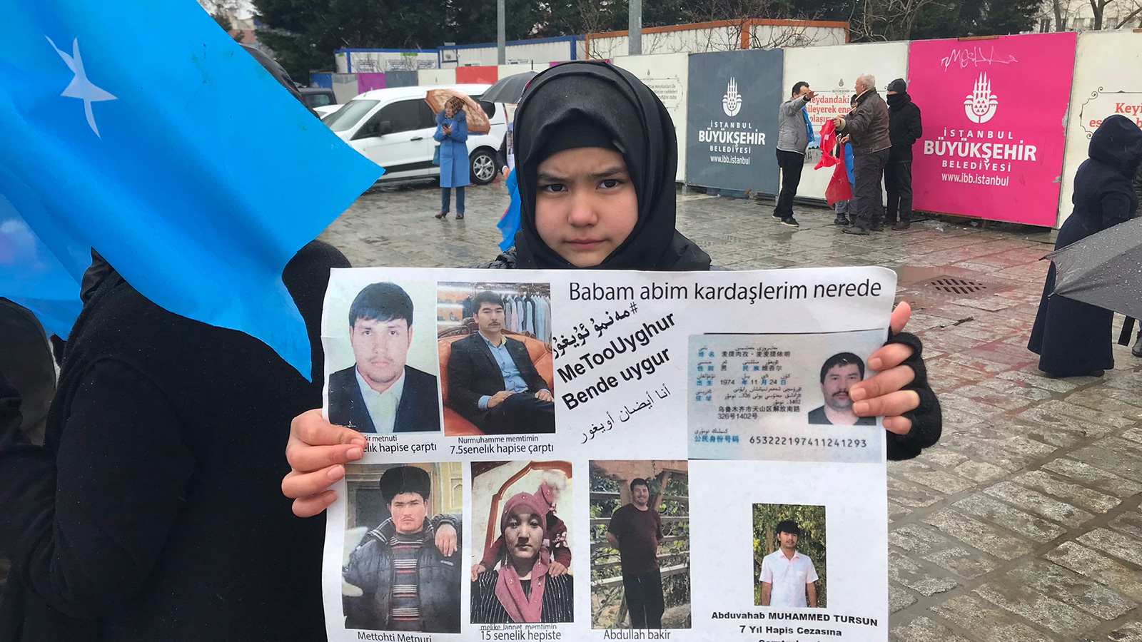‪طفلة من الإيغور ترفع صور أقارب لها‬ (الجزيرة نت)