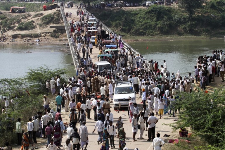 People cross a bridge after a stampede near Ratangarh temple in Datia district in the central Indian state of Madhya Pradesh October 13, 2013. A stampede at a bridge leading to a remote Hindu temple in Madhya Pradesh on Sunday killed at least 89 people and injured more than 100, police said. Nearly 150,000 devotees gathered to celebrate Dussehra at the Ratangarh temple, in a forest outside the town of Datia, 390 km (240 miles) north of Bhopal. But pilgrims panicked when the railings broke on a bridge that led to the temple, triggering the stampede. Some devotees were crushed to death under the feet of fellow worshippers, others drowned after falling or jumping into the river Sindh. REUTERS/Stringer (INDIA - Tags: DISASTER RELIGION)