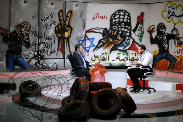 Palestinian presenter Raji Al-Hams (R) listens to Hamas official Salah al-Bardweel at the studio of Hamas-run Al-Aqsa TV in Gaza City October 27, 2015. The studio of Hamas-run Al-Aqsa TV is decorated with slogans praising the