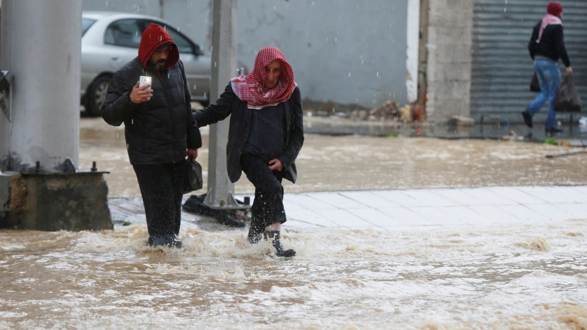 People cross a flooded street during heavy rains in Amman, Jordan, February 28, 2019. REUTERS/Muhammad Hamed