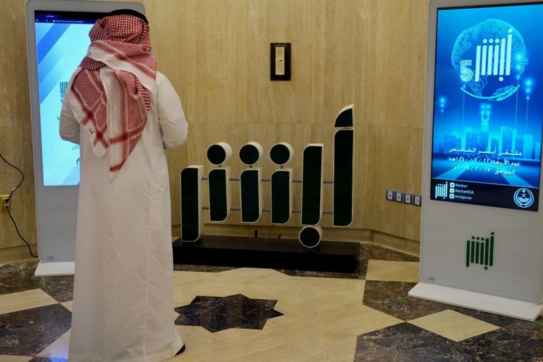 A Saudi Interior Ministry employee stands in front of a screen displaying the Absher mobile app logo at the ministry in Riyadh on Feb. 19. (Fayez NureldineAFPGetty Images) copy.jpg