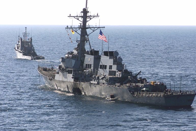 380991 01: The U.S. Navy destroyer USS Cole is towed away October 29, 2000 from the port city of Aden, Yemen, into open sea by the Military Sealift Command ocean-going tug USNS Catawba. Sailors lined the deck of the Cole, saluting a giant U.S. flag to the national anthem as the destroyer damaged in an apparent suicide bombing was towed out of Aden's port and headed home. (Sgt. Don L. Maes/U.S. Marine Corps via Newsmakers)