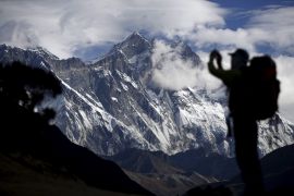 A tourist is silhouetted as he takes pictures of Mount Nuptse (C) as Mount Everest (L) is covered with clouds in Solukhumbu district, also known as the Everest region, in this picture taken November 30, 2015. To match Insight QUAKE-NEPAL/SHERPAS REUTERS/Navesh Chitrakar