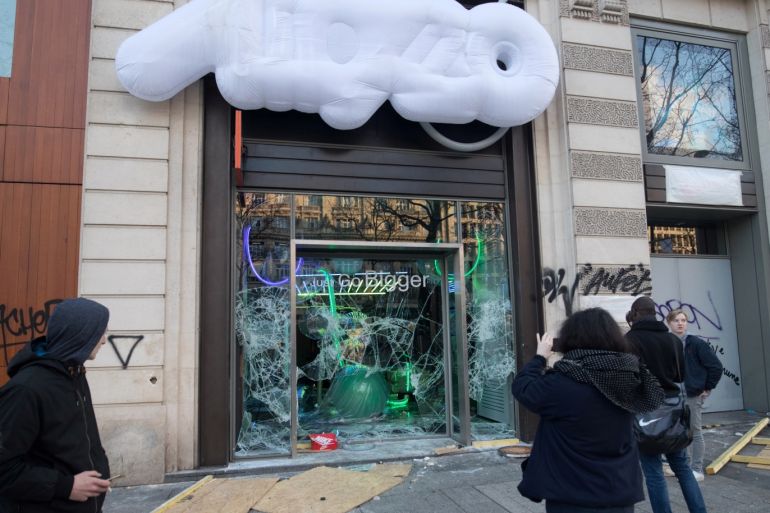 People take pictures of a damaged shop during a demonstration by the