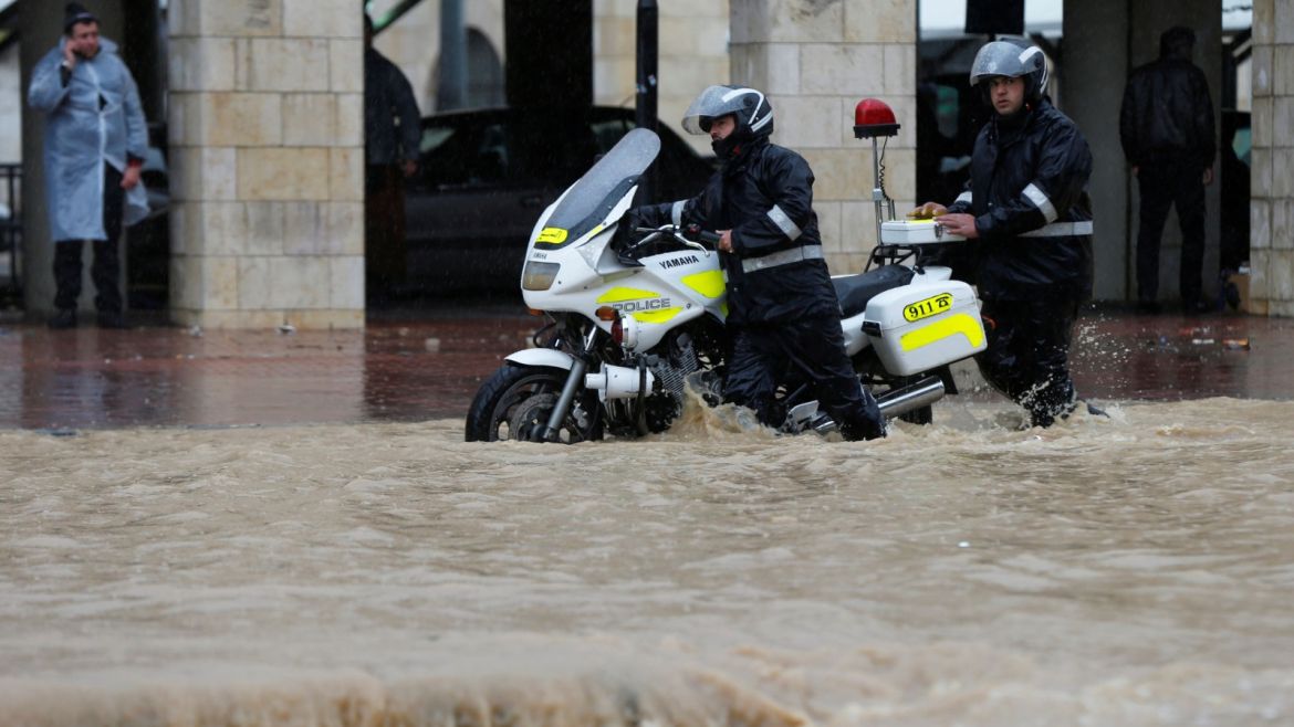 Traffic policemen push a motorcycle through a flooded street during heavy rains in Amman, Jordan, February 28, 2019. REUTERS/Muhammad Hamed