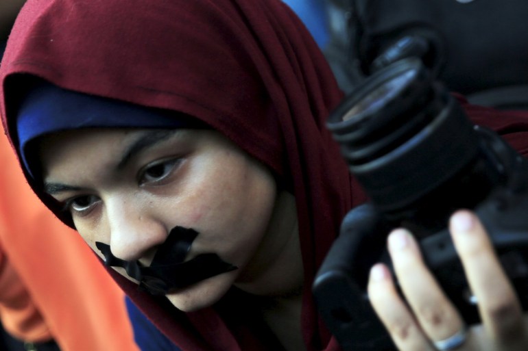 A news photographer with her mouth taped and holds up her camera during a protest against the detention of Ahmed Ramadan, a photojournalist with Egyptian private newspaper
