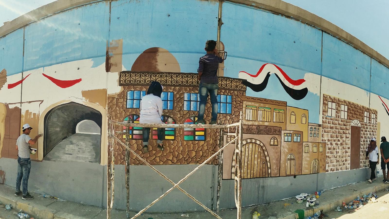 ‪فريق ثورة الفن يرسم على جدارية نفق باب سنجار‬ (الجزيرة)